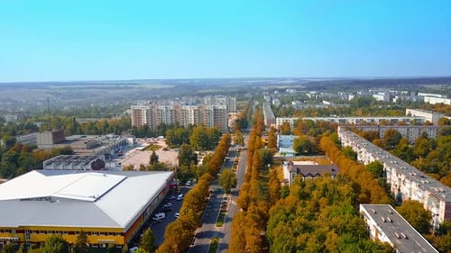 Flying along the road through the provincial city. Aerial view over the multi-storied buildings