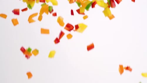 Brightly colored red, green, yellow and orange diced bell pepper fresh vegetable pieces raining down