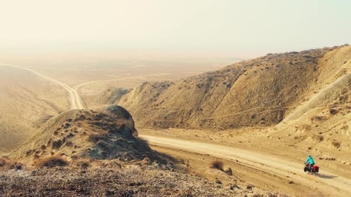 Cyclist Rides Through a Remote, Arid Desert
