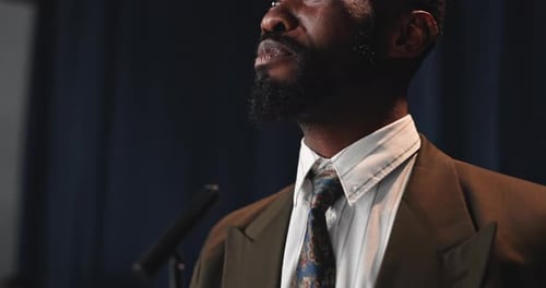 Man Speaking at Microphone in a Suit Jacket