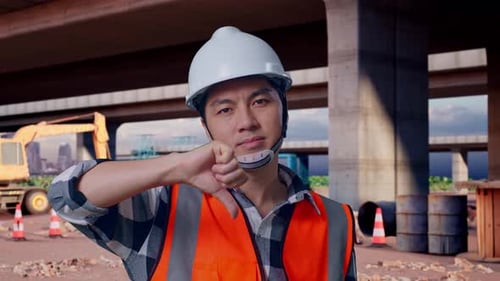 Asian Male Engineer Showing Thumbs Down Gesture And Shaking His Head At Building Site