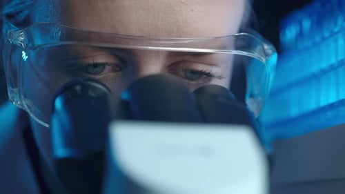 Woman Scientist Examining Sample with Microscope in Lab