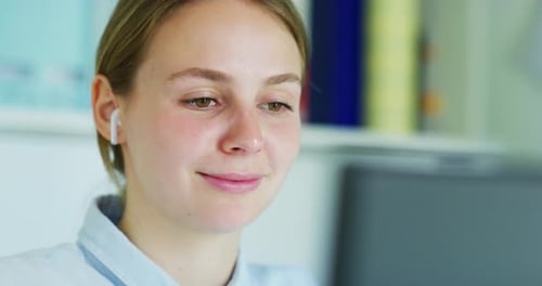 Close up of an Young Blond Woman with Earphones is Making a Video Conference Call with a Computer