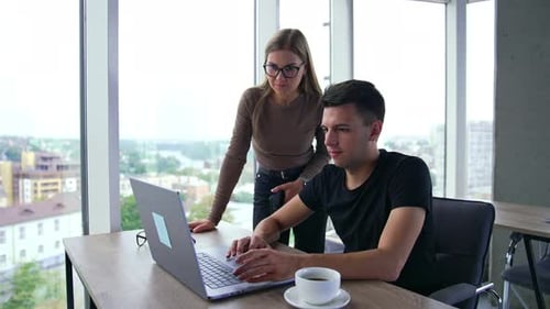 Coworkers Collaborating on Laptop in Bright Office