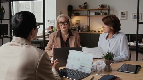 Three Middle-Aged Caucasian Businesswomen Having Discussion in Modern Office