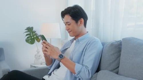 Man Sitting on Couch Using Mobile Phone