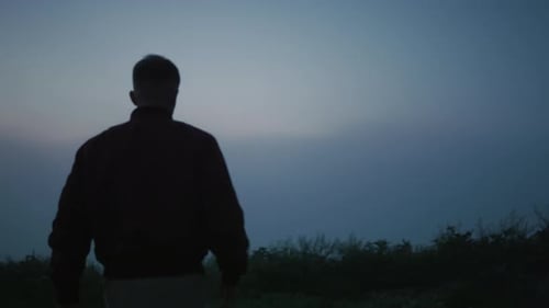 Back View Young Guy Walking in Field at Morning. Casual Man Hiking