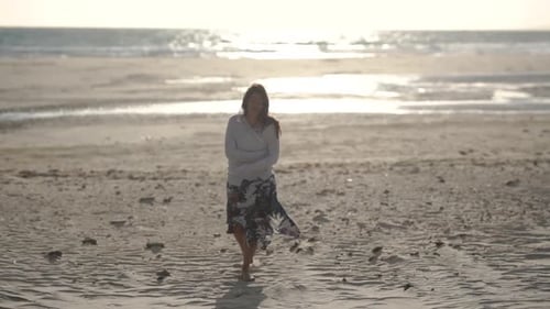 Young women walks towards camera on sandy beach at sunset, relaxing, smiling, happy. Gibraltar, Spai