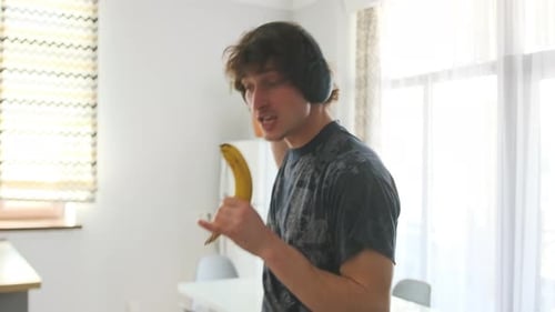 Energetic Man Dancing with Banana in Kitchen