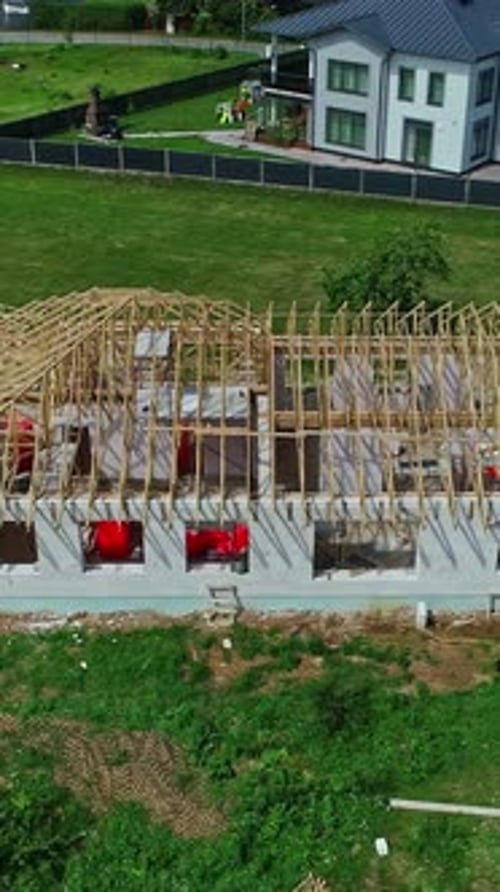 Aerial view of a new house under construction with exposed wooden roof trusses