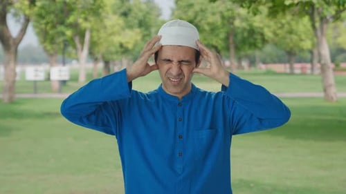 Sick Muslim man suffering from Headache in park