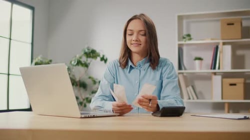 Satisfied Young Woman Accountant Use Calculator to Check Sums in Annual Report