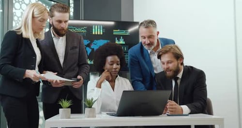 Diverse Team Analyzes Data on Laptop in Office