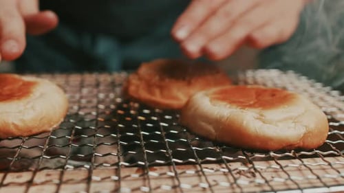 Frying burger buns on hot smoky outdoor grill. Close up, slow motion.