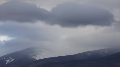 Timelapse of moving clouds in mountains with snow. Creative. Covering clouds in snowy rocky mountain