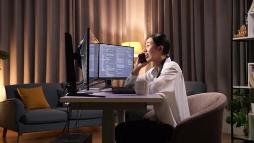 Une programmeuse asiatique parle sur un smartphone tout en créant une application de développement d'une Appli d'ingénieur logiciel