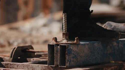 Worker Tightening Formwork Wing Nut with Hammer During Assembly