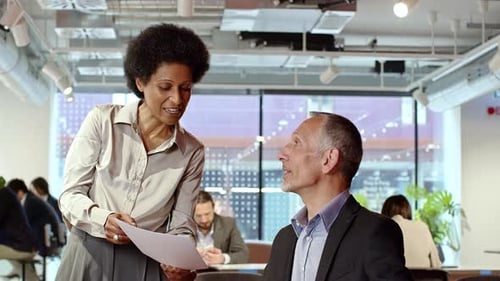 Professional Woman Discussing Documents with a Man in Office