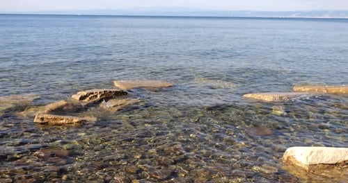 Sun glare in the crystal clear water of the Adriatic Sea on the coast, stones and shells underwater
