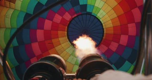 Slow motion close up view of the flame inside of a colorful hot air balloon being inflated before