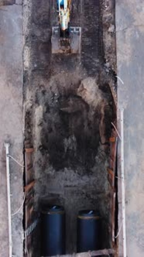 Road construction work, top down aerial shot, excavator digging, sewage pipes