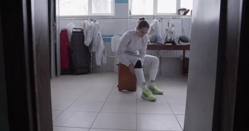 Young Woman Preparing Fencing Gear in Locker Room