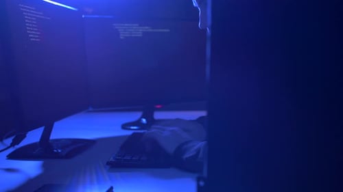 Male hacker typing malicious code for a cyber attack in a dark room