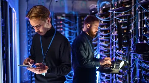 Zwei Männer programmieren in einem Serverraum