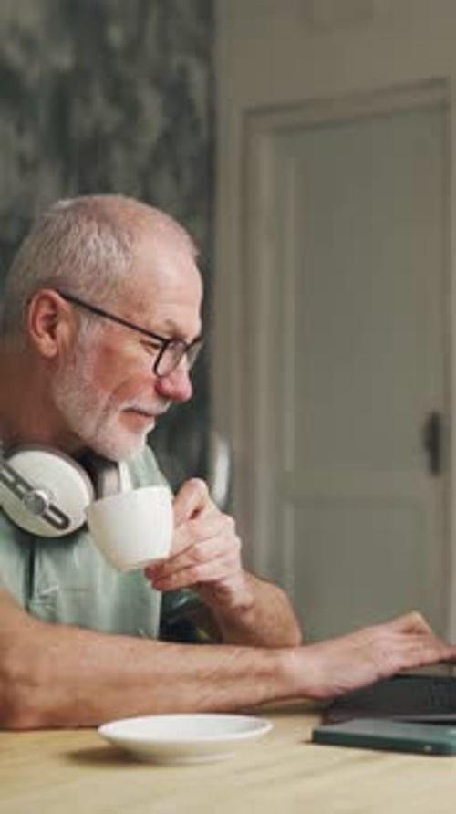 Work From Home An Old Man in His 60s Works on a Computer Elderly Pensioner Man Typing on Laptop
