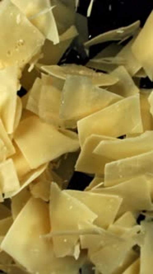Parmesan Cheese Flakes Fly Upwards on a Black Background Filmed on a Highspeed Camera at 1000 Fps