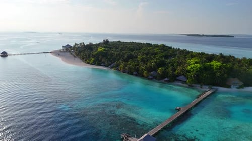 Aerial View Zoom in of Tropical Maldives Island with Wooden Pier Surrounded By Turquoise Sea Bright