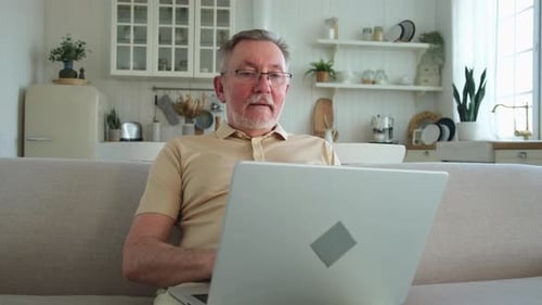 Senior Man Using Laptop on Couch at Home