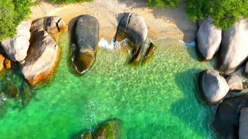 Stunning sandy beach with rock, clean sea water and green forest. 4K.