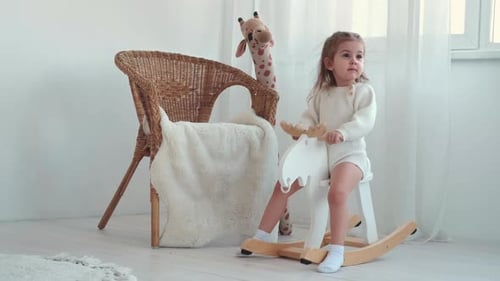 Child Playing on Rocking Horse in Bright Room