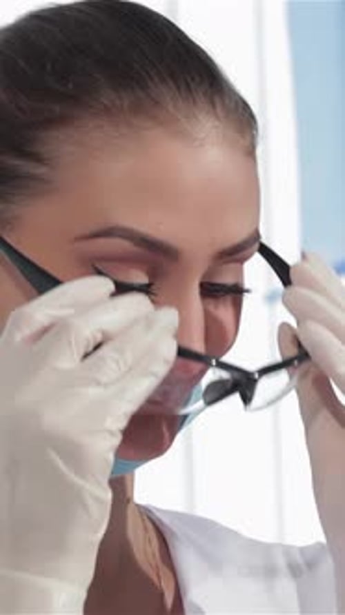 Caring Female Dentist Examines Her Patient with Protective Glasses
