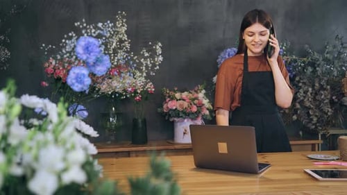 Female Florist Talking on Smartphone in Flower Shop