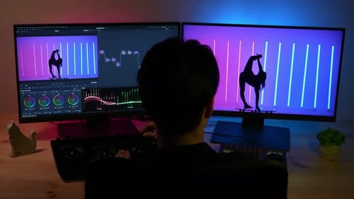 Primer plano a espaldas de un hombre trabajando en el ordenador mirando el monitor editando vídeo con un mezclador