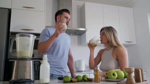 Pareja disfrutando juntos de un batido casero en una cocina moderna