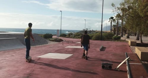 Young people having fun at skateboard park outdoor during sunset