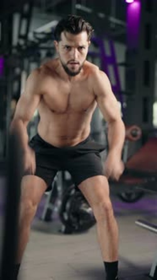 Muscular Man Working Out with Battle Ropes at the Gym
