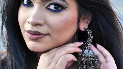 Stylish Woman Adorns Herself with Ornate Earrings Outdoors