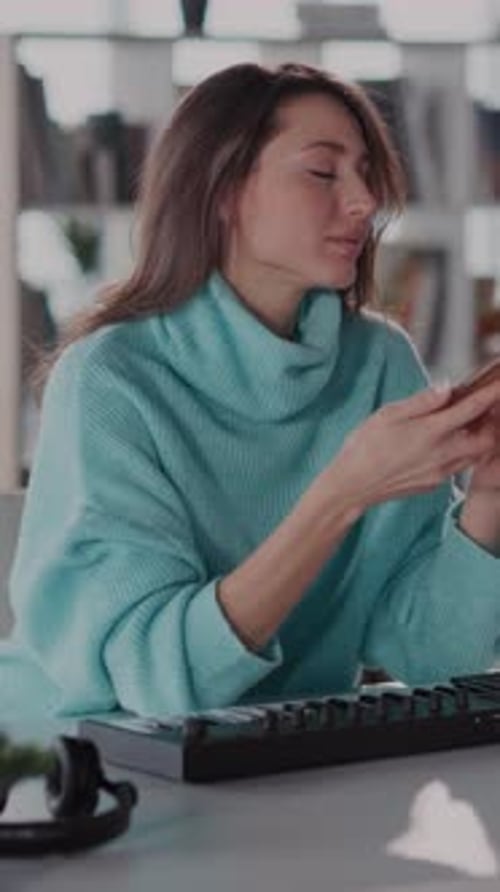 A Woman in a Blue Sweater Multitasks in a Cozy Home Office