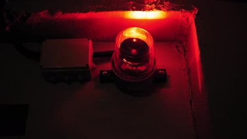 Closeup of a Rotating Red Emergency Siren Lamp on the Wall of a Dark Tunnel