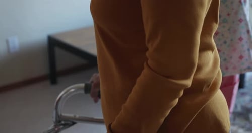 Senior Woman Using Walker with Caregiver Nearby
