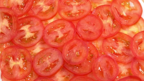 Sliced fresh tomatoes like carpaccio rotate as background. Preparations for pizza or vegetable