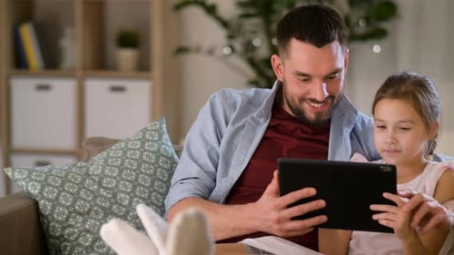 Father and Daughter Using Tablet on Couch