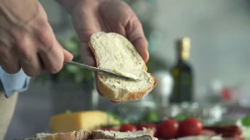 Close Up of Male Hands Spreading Butter on Bread in Kitchen Adult