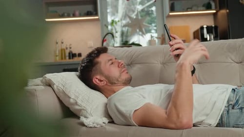 Man Relaxing on Couch Using Mobile Phone