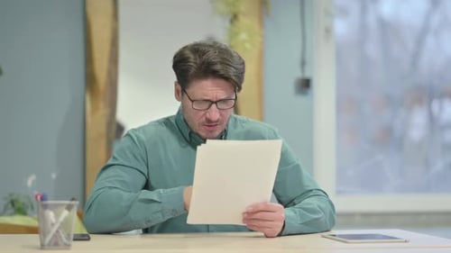 Upset Man Reading Documents at Desk