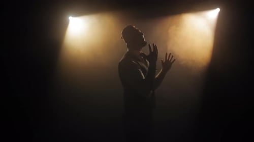 Silhouetted Figure Performing in Dark Stage Lighting